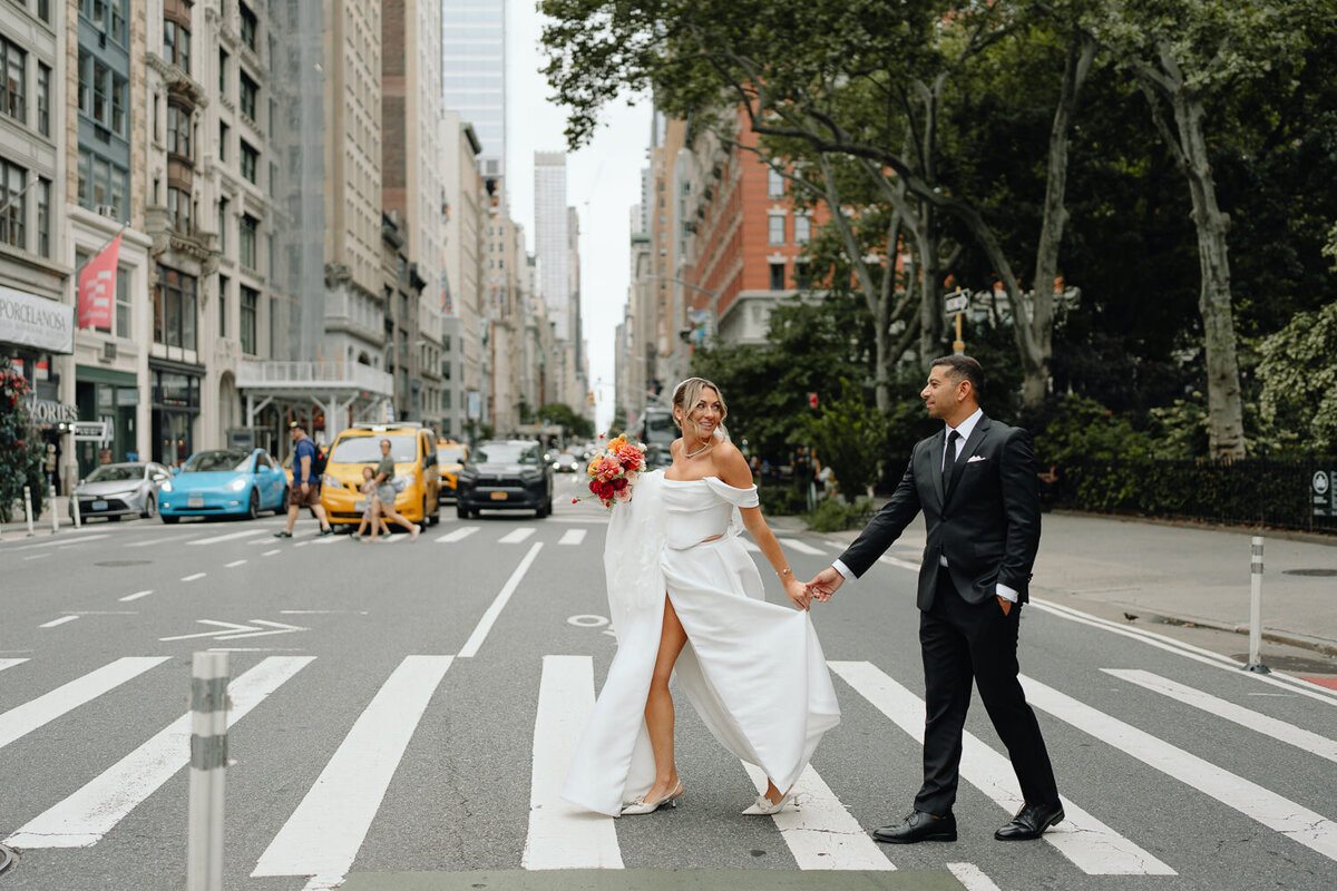 Bride and groom walking hand in hand across a Manhattan street